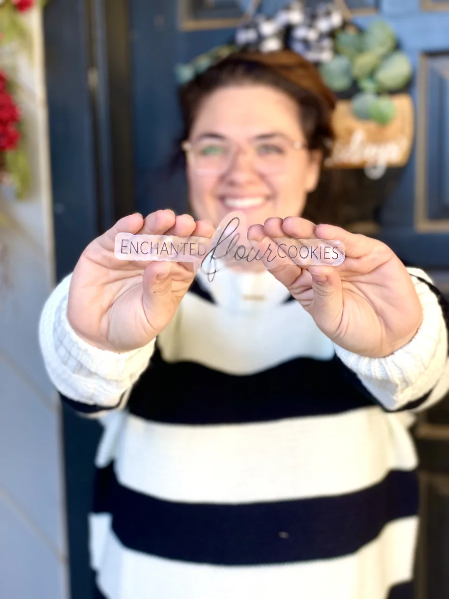 Danielle smiling and holding an Enchanted Flour Cookies acrylic logo